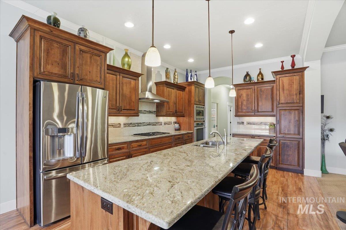Kitchen featuring tasteful backsplash, stainless steel appliances, light wood-style flooring, a breakfast bar, and pendant lighting