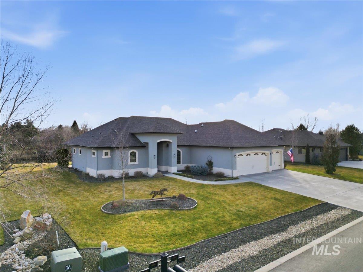 View of front of property featuring stucco siding, driveway, a front yard, and an attached garage
