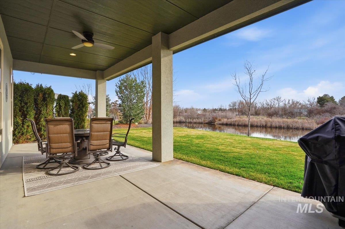 View of patio featuring a grill, outdoor dining area, a ceiling fan, and a water view