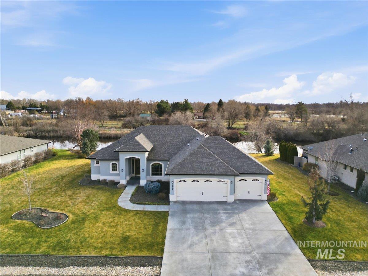 French provincial home featuring a front yard, an attached garage, roof with shingles, driveway, and stucco siding