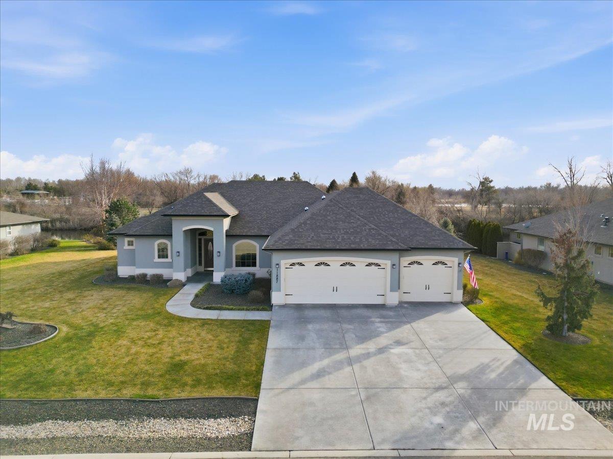 View of front of property featuring a shingled roof, a front lawn, a garage, driveway, and stucco siding