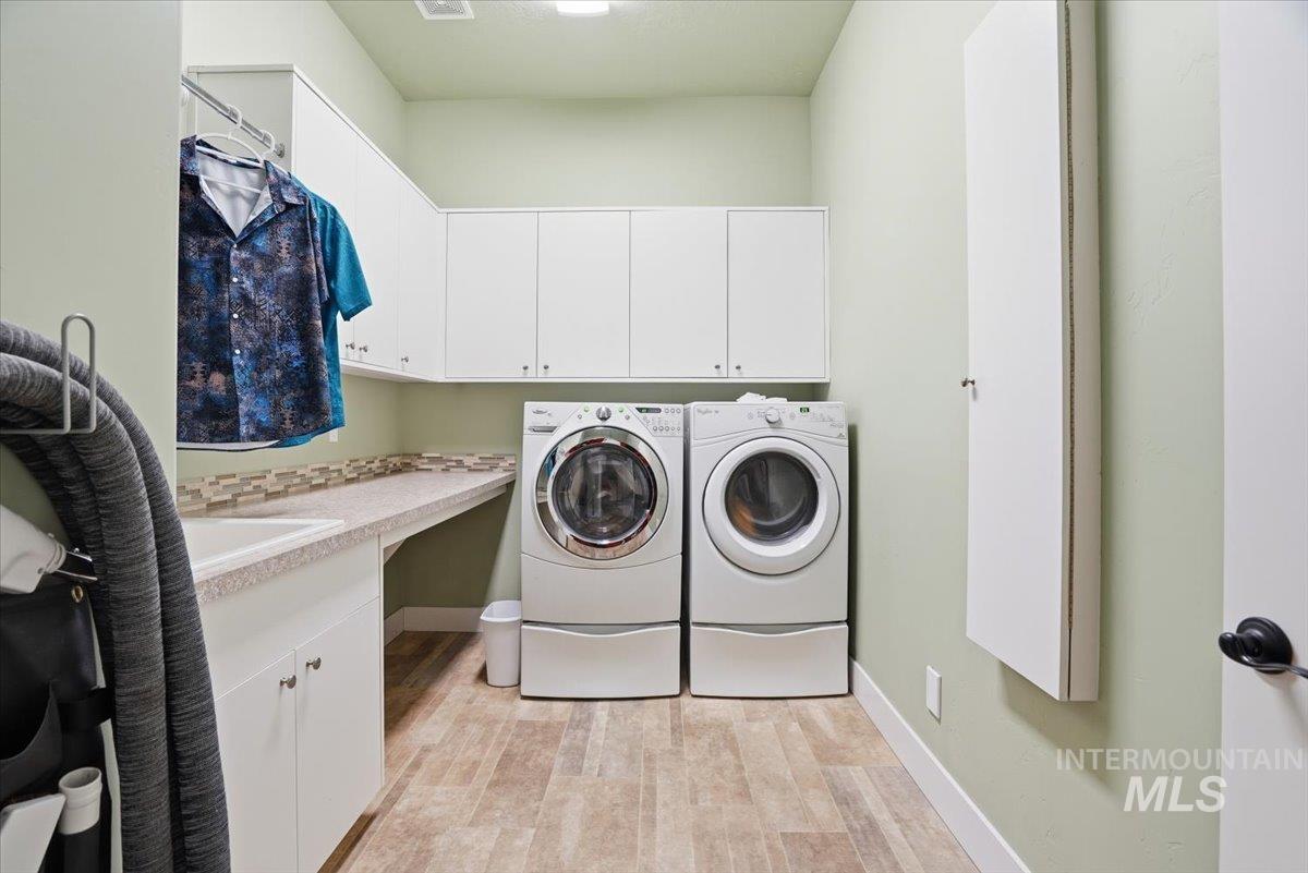 Laundry room featuring light wood-style flooring, washing machine and dryer, and cabinet space