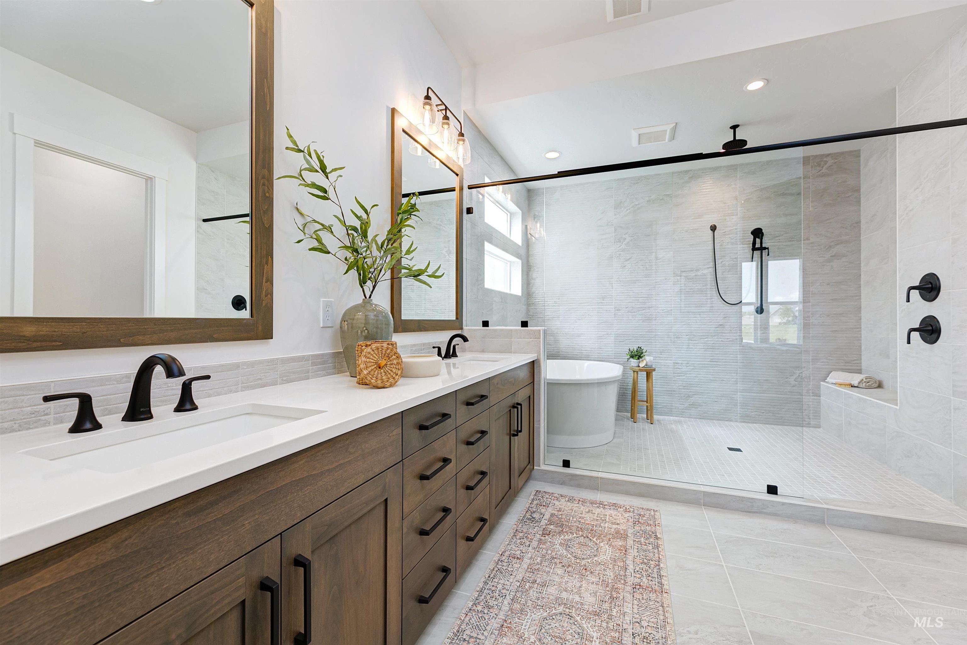 Bathroom featuring double vanity, tiled shower, a freestanding bath, light tile patterned floors, and recessed lighting