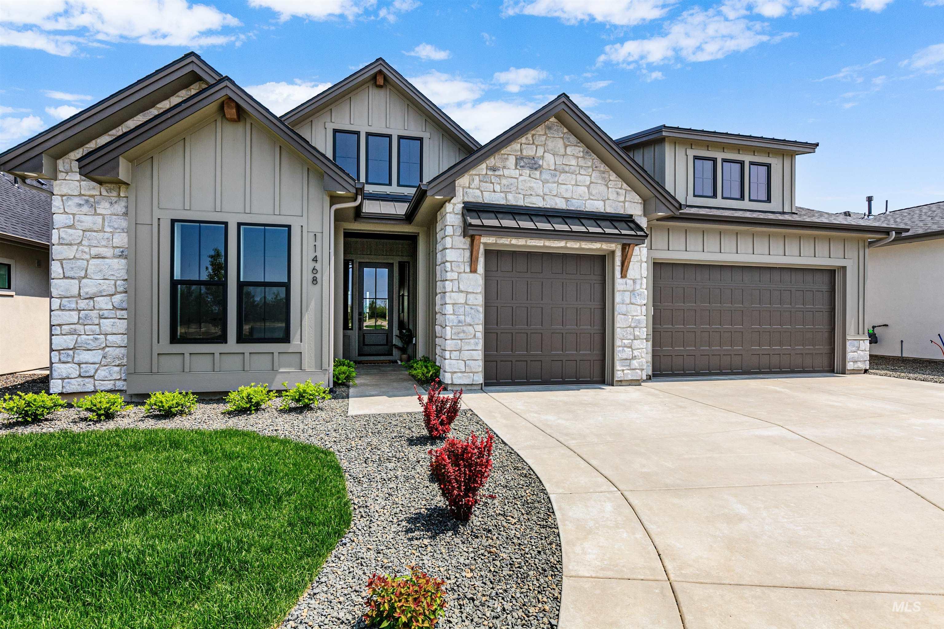 View of front of home featuring concrete driveway, board and batten siding, an attached garage, stone siding, and a front yard