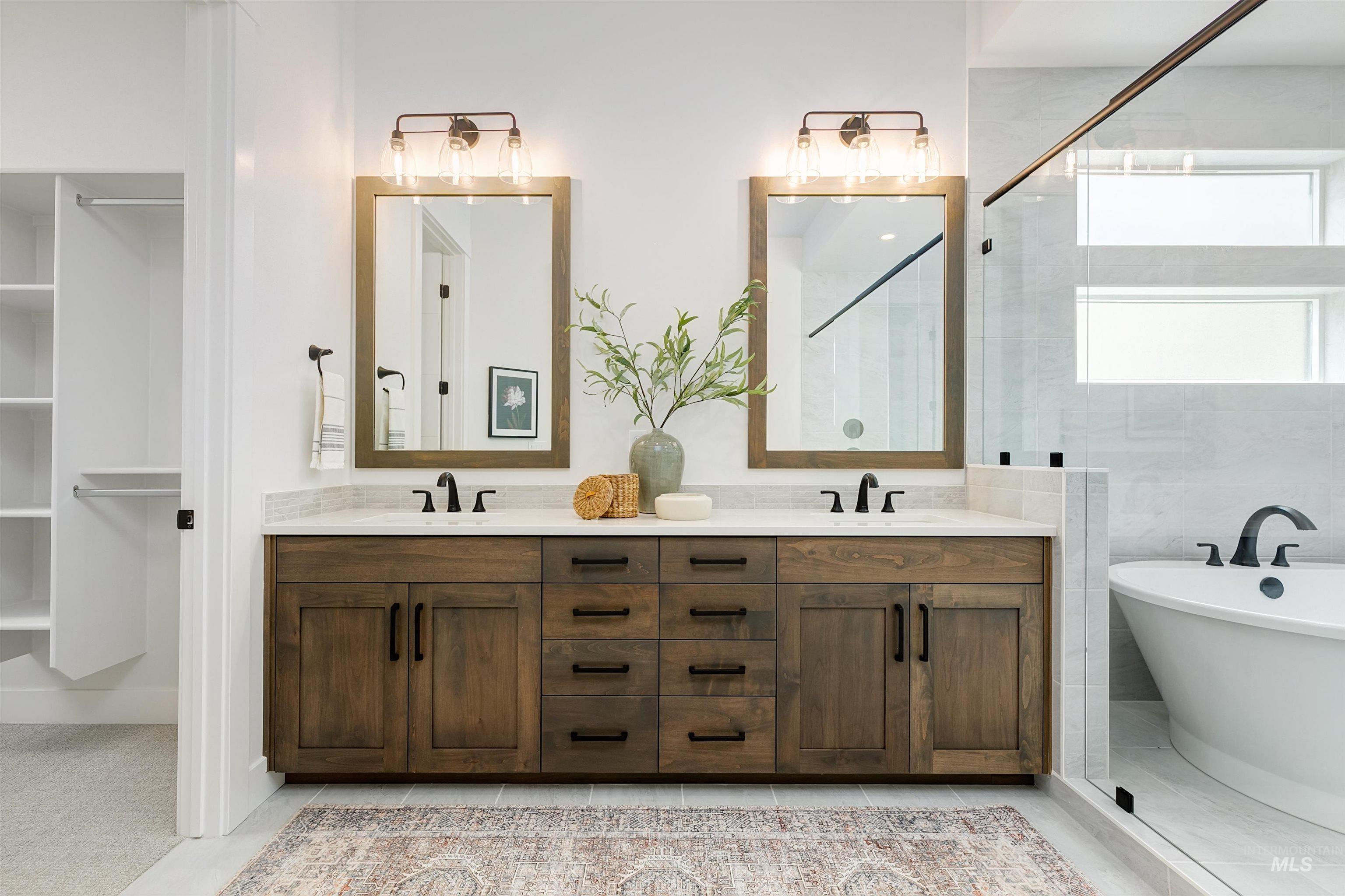 Full bathroom featuring double vanity, a freestanding bath, and tiled shower