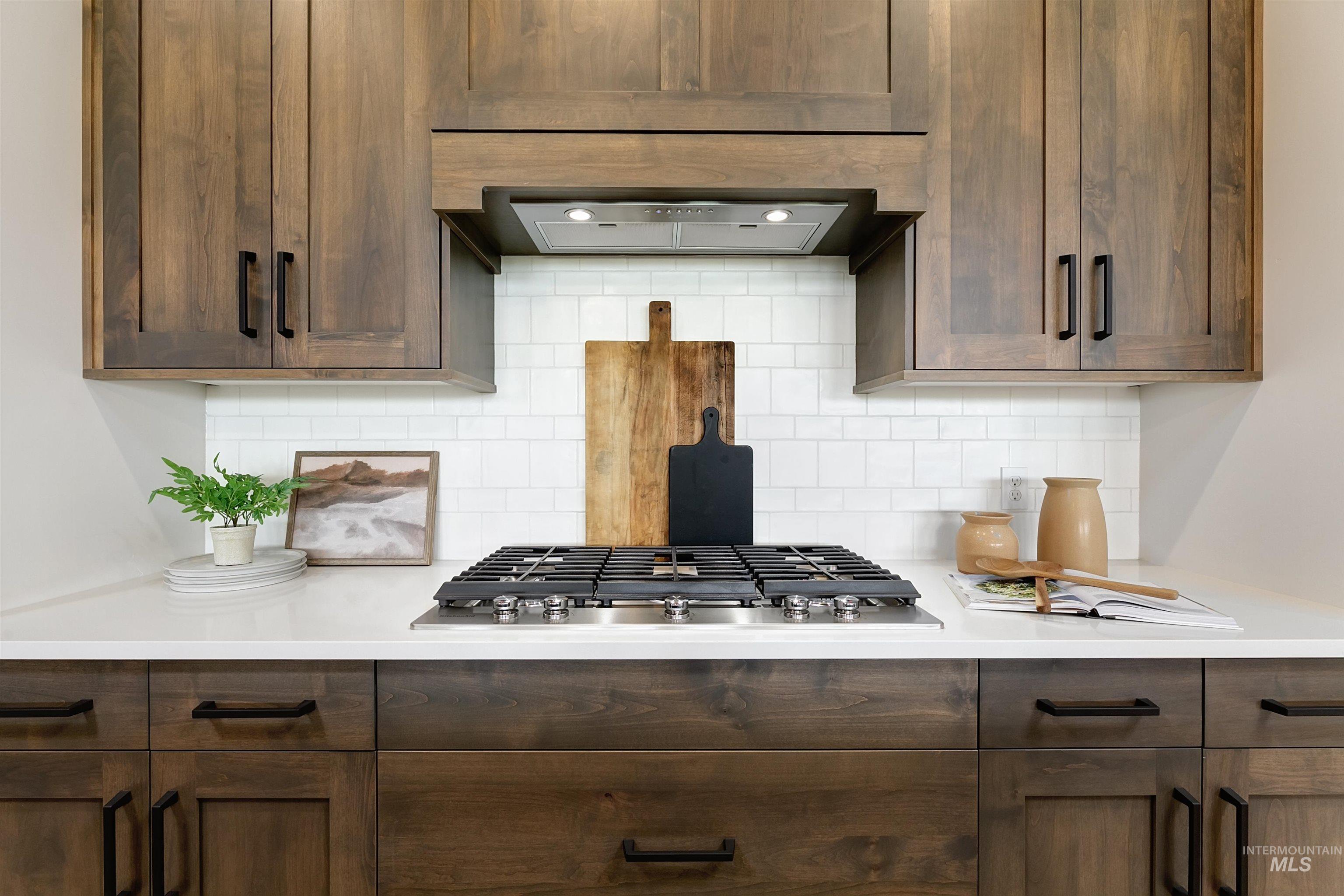Kitchen featuring dark wood finish cabinets, stainless steel gas stovetop, and decorative backsplash