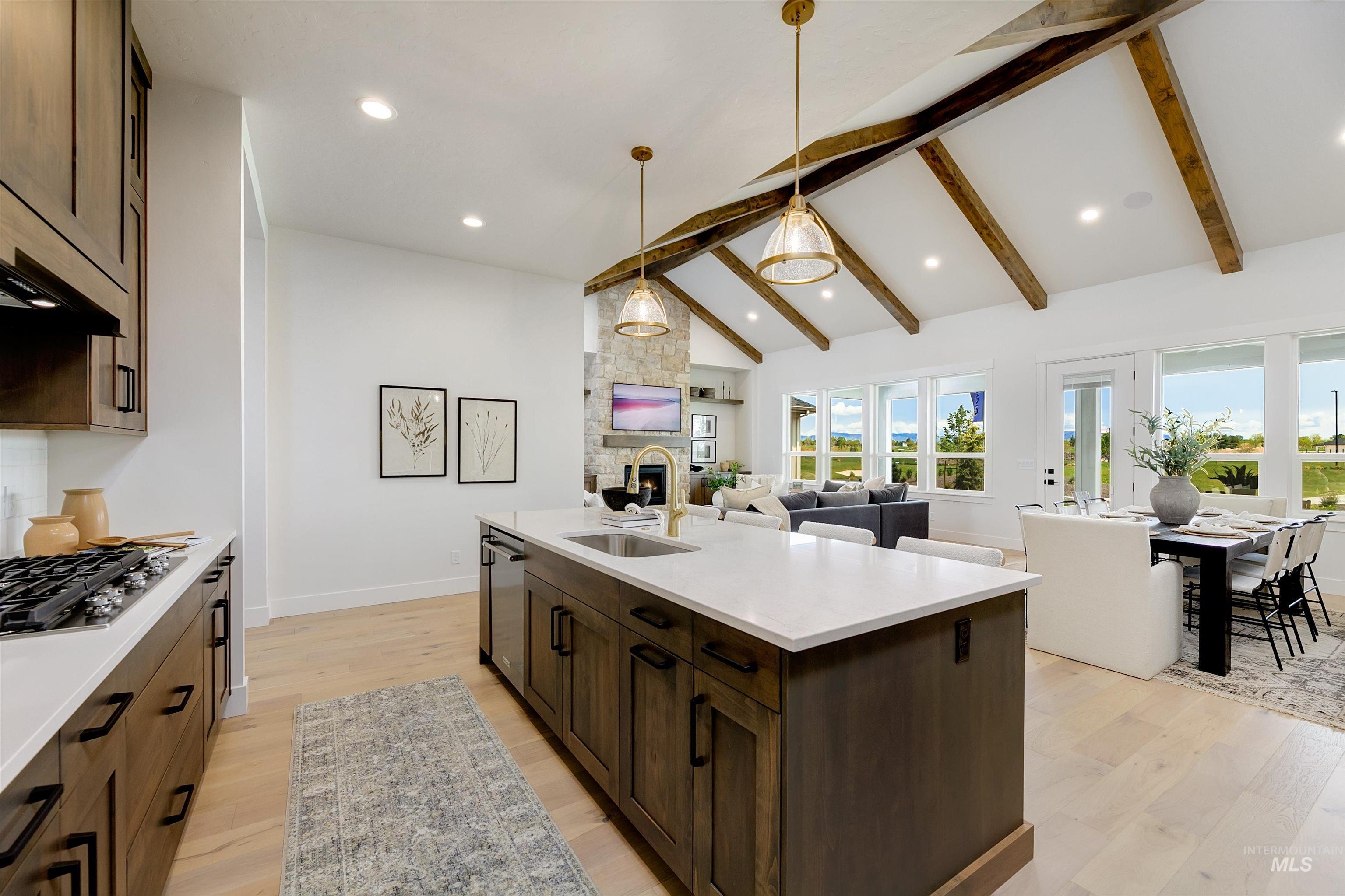 Kitchen with light wood-style floors, dark wood finish cabinetry, open floor plan, lofted ceiling, and a stone fireplace