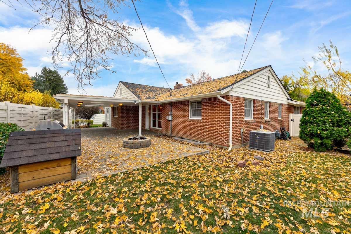 Rear view of house with a patio area, brick siding, an outdoor fire pit, and a chimney