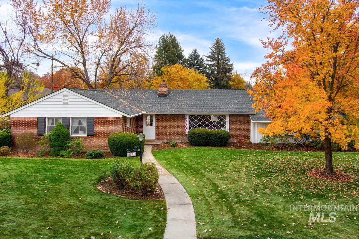 Single story home featuring a front yard, brick siding, a chimney, and roof with shingles