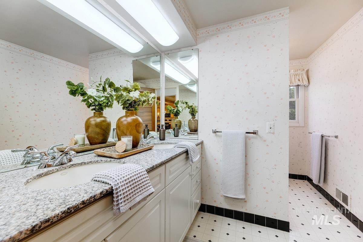 Full bath featuring wallpapered walls and double vanity