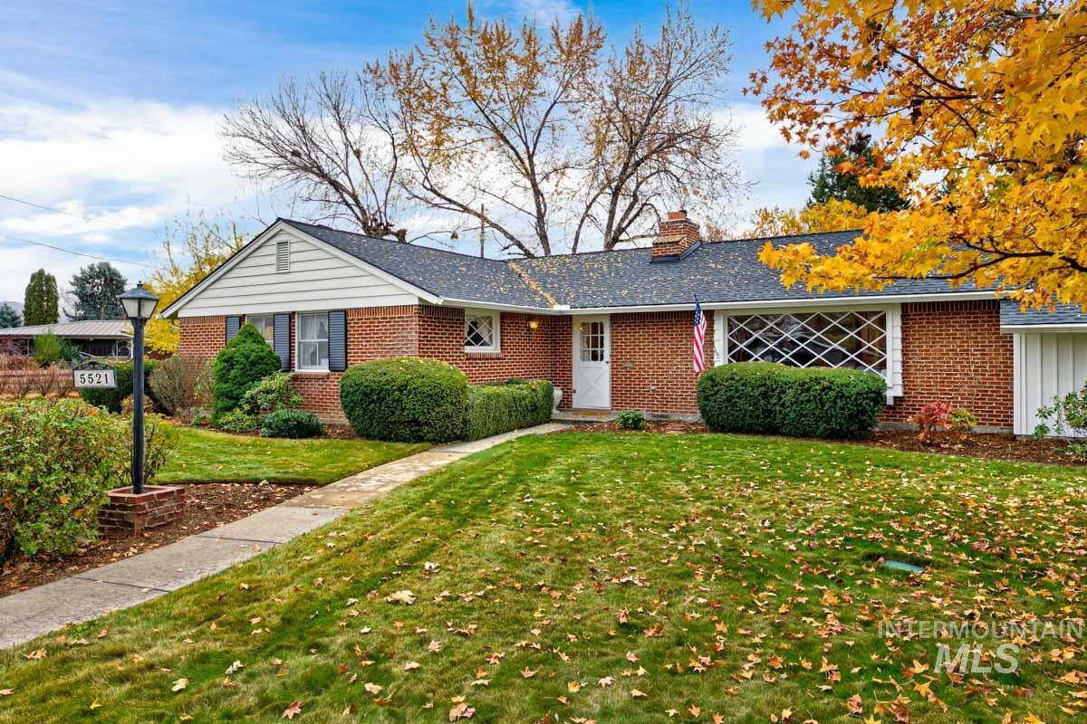 Single story home with a front yard, a chimney, and brick siding