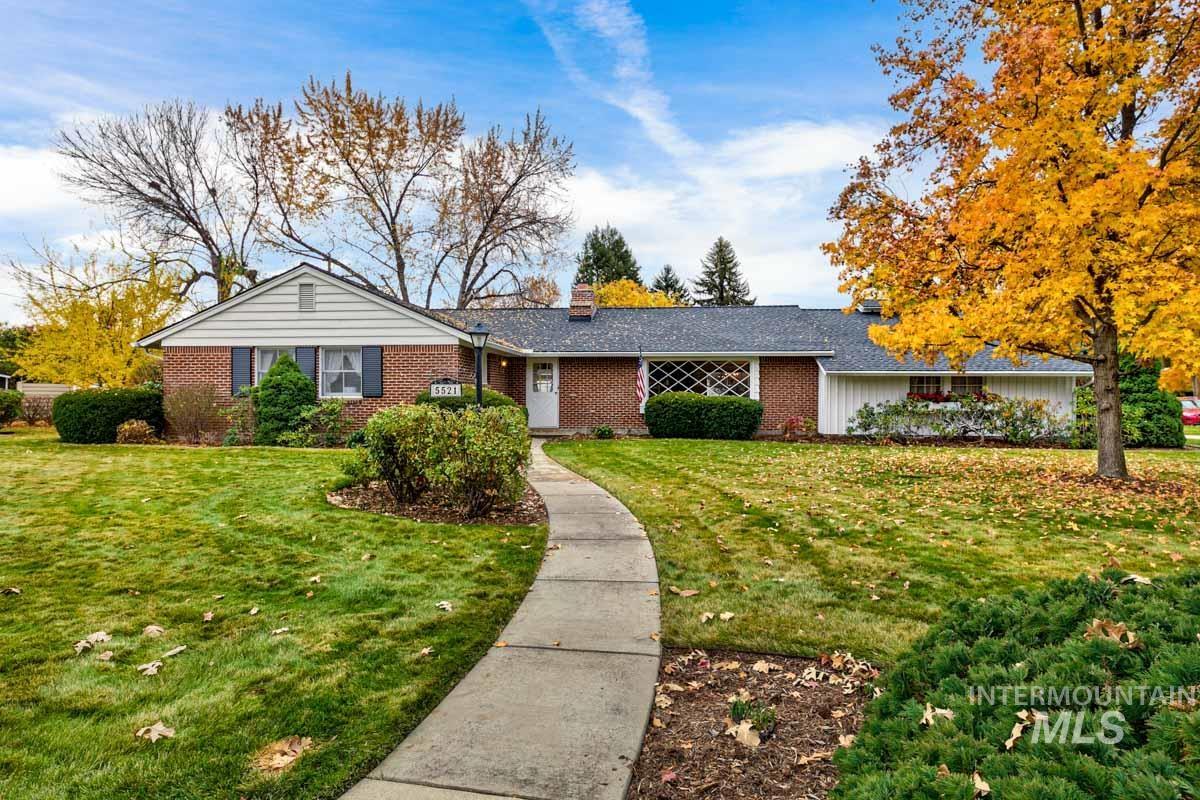 Ranch-style house with a front yard, a chimney, and brick siding