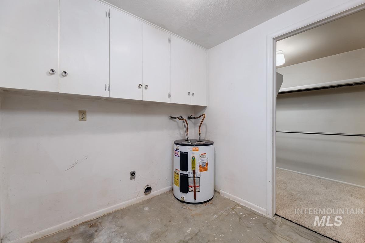 Laundry room with electric water heater, cabinet space, electric dryer hookup, and concrete flooring