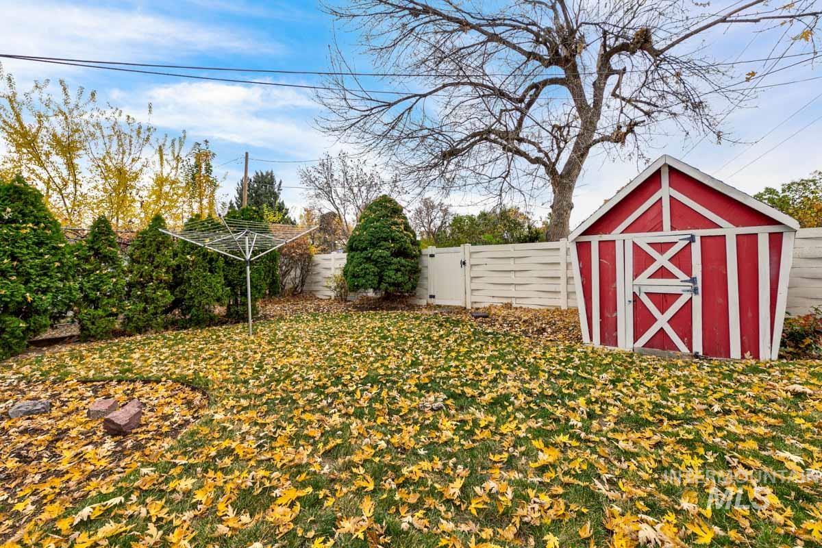 Fenced backyard featuring a storage unit