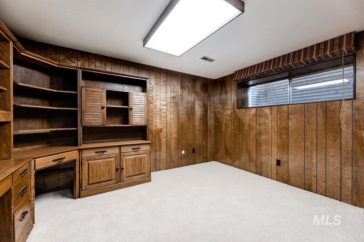 Unfurnished office featuring carpet, wooden walls, and built in desk