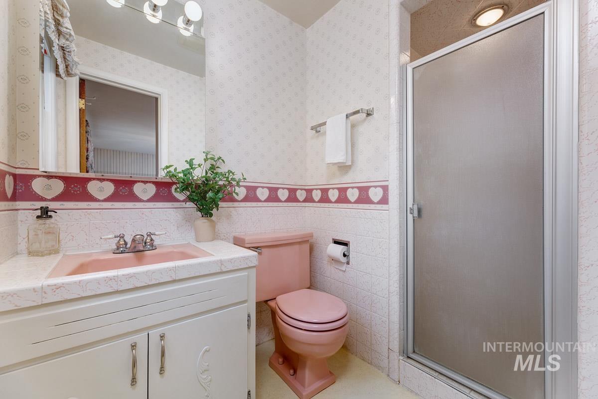Full bath featuring vanity, a shower stall, tile walls, light tile patterned floors, and a wainscoted wall