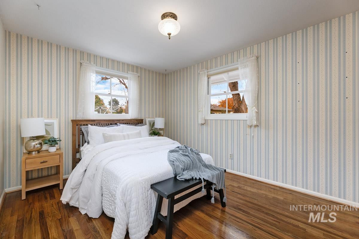 Bedroom featuring dark wood-style flooring and wallpapered walls