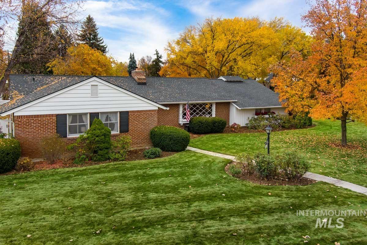 Ranch-style house featuring a front lawn, brick siding, a chimney, and a shingled roof