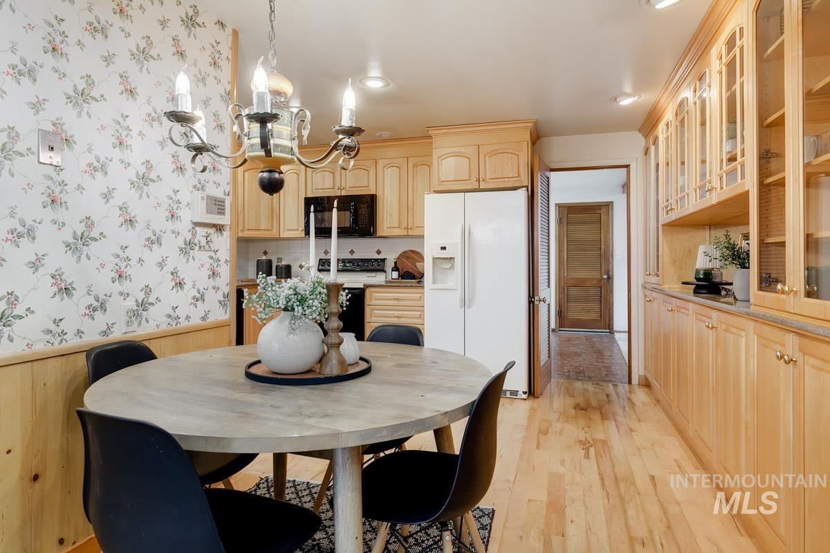 Dining area featuring light wood finished floors, a chandelier, a wainscoted wall, and recessed lighting
