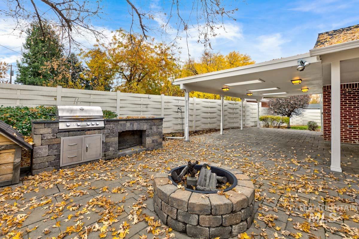 Fenced backyard with a fire pit, an outdoor kitchen, and a patio