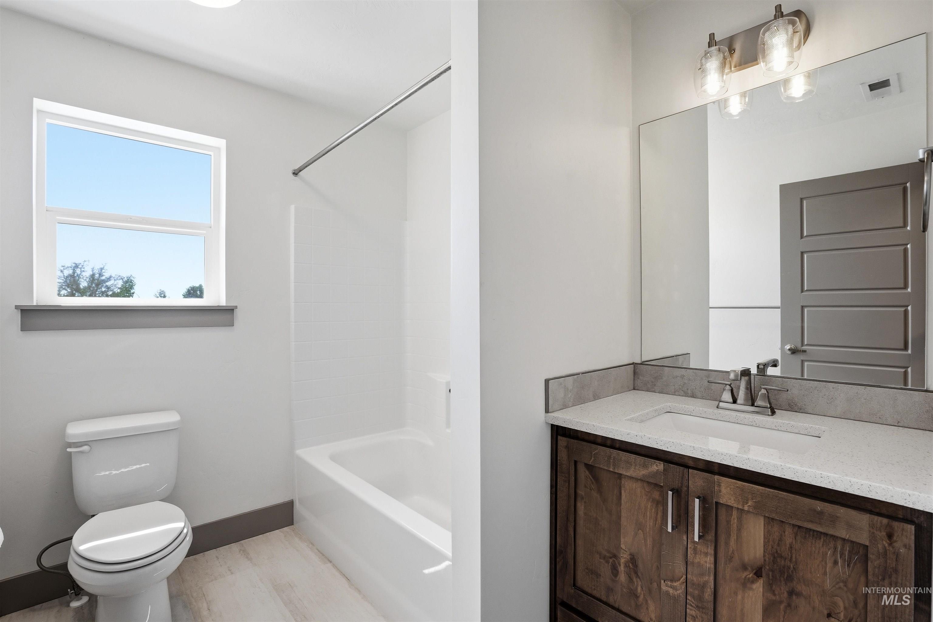 Modern bathroom featuring a wood-finish vanity with a light-toned countertop, an integrated sink, and an overhead vanity light fixture