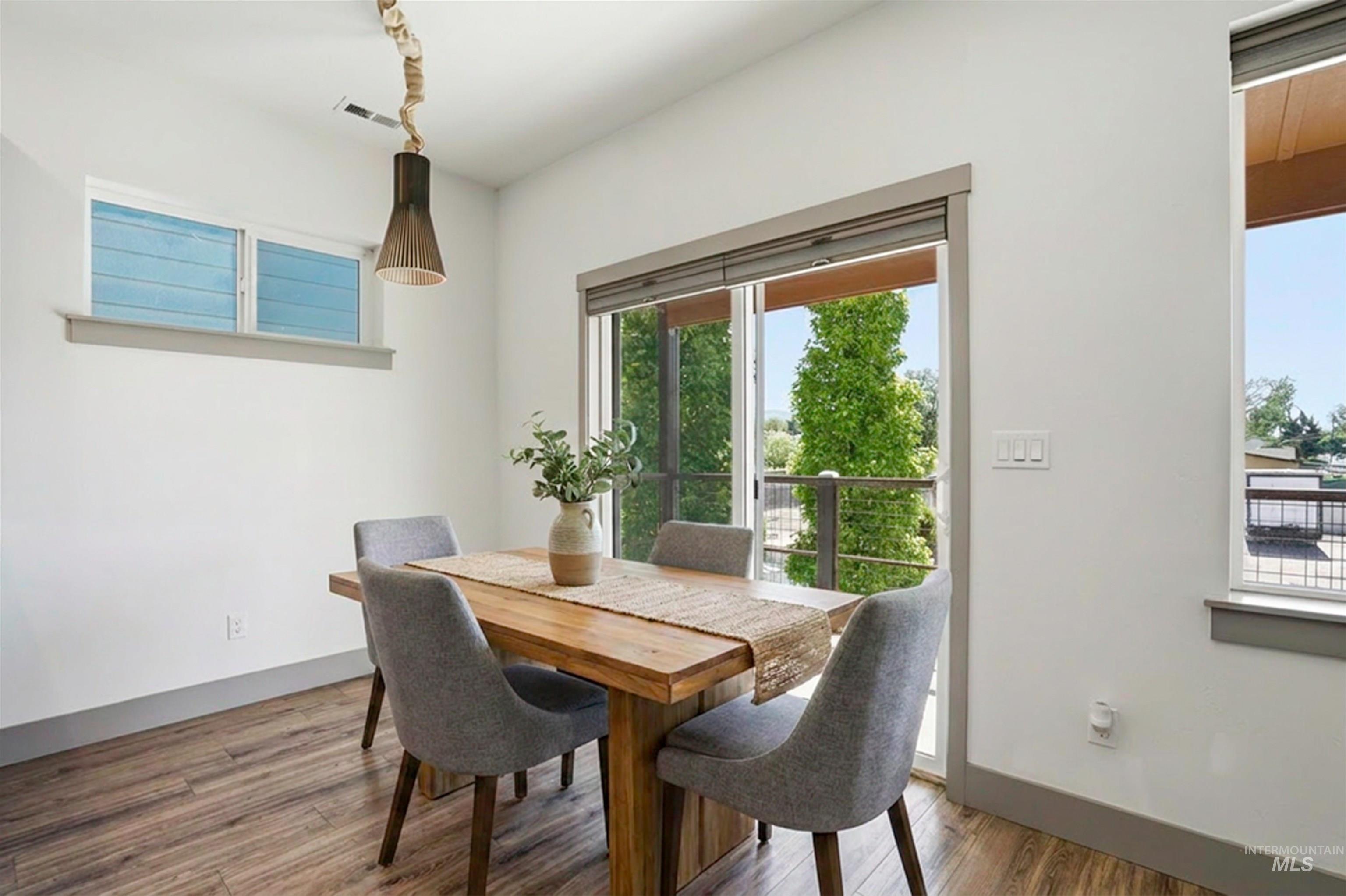 Bright dining area featuring wood-finish flooring and a contemporary pendant light fixture