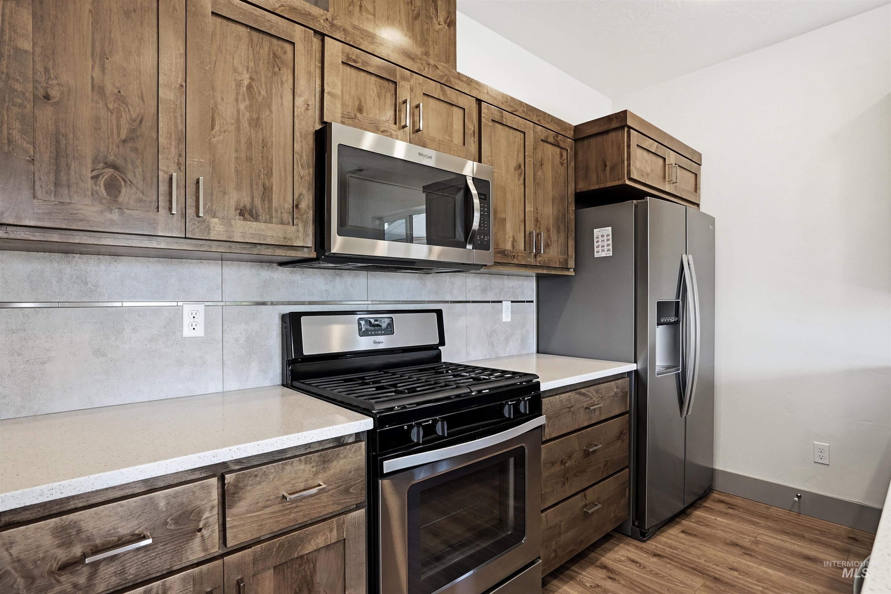 Kitchen featuring wood-finish cabinetry, light-colored countertops, and a tiled backsplash