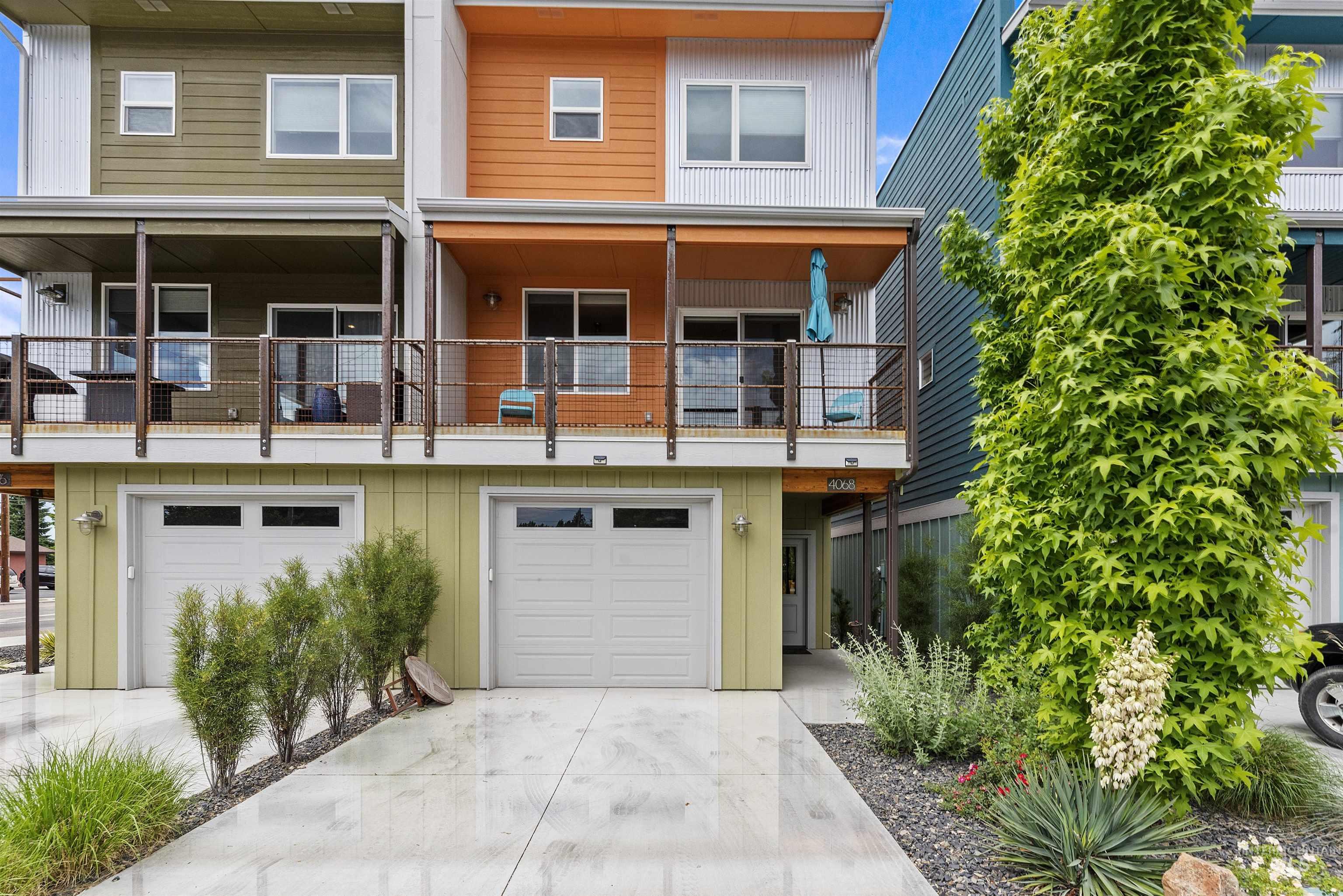 Contemporary multi-level exterior featuring varied siding materials, private balconies with cable railings, and integrated single-car garages