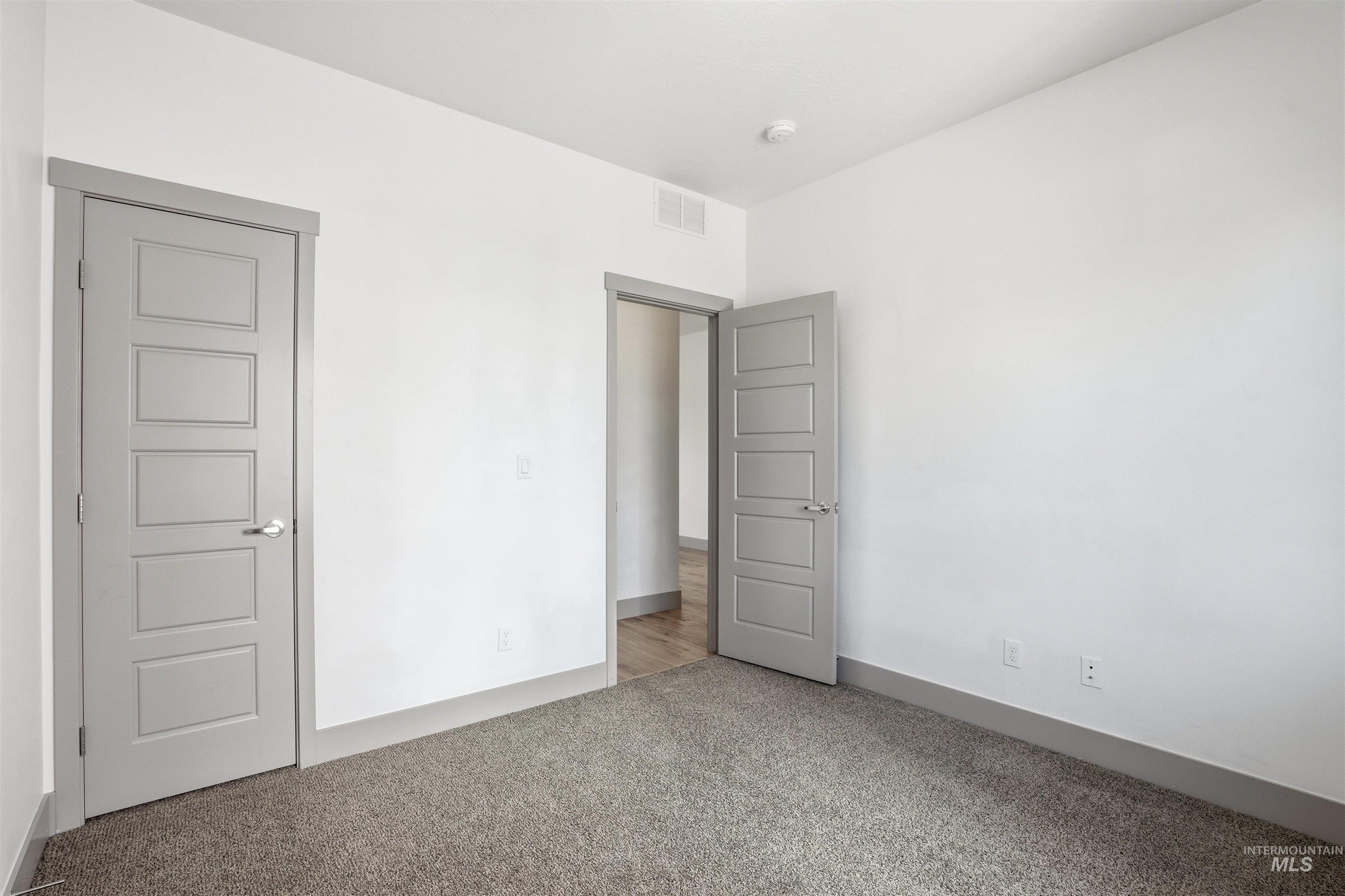 Spacious room with plush gray carpet, crisp white walls, and contemporary five-panel doors with satin nickel hardware