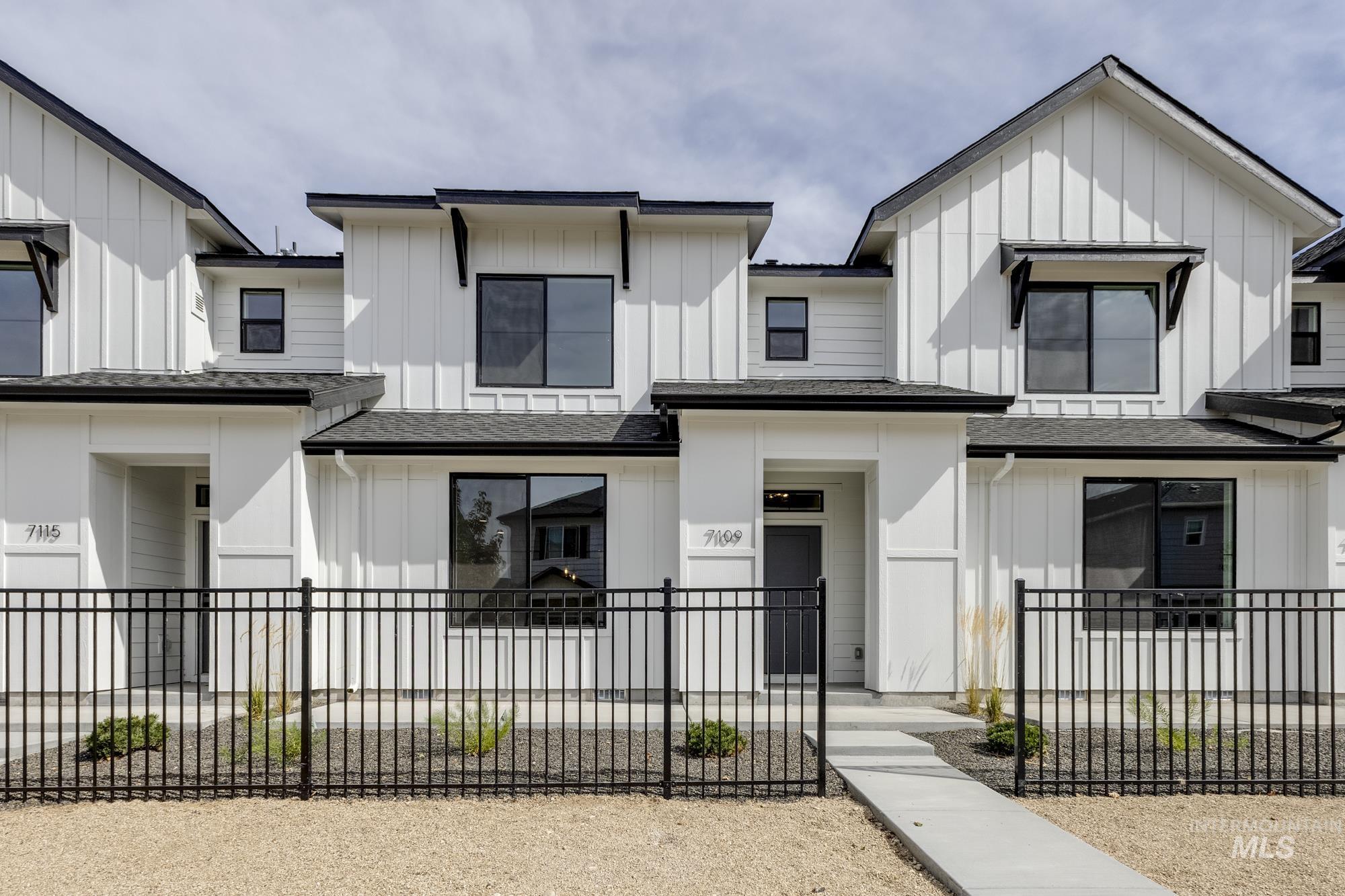 Modern farmhouse featuring board and batten siding, roof with shingles, a fenced front yard, and covered porch