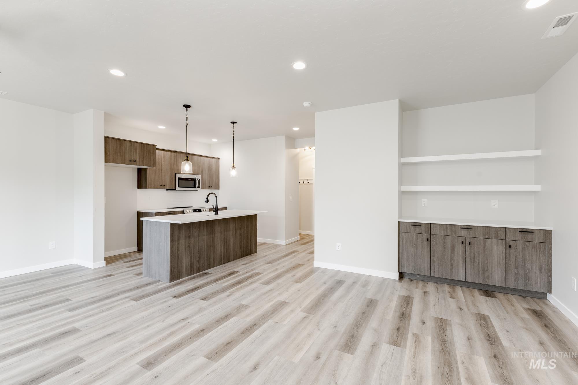 Kitchen featuring recessed lighting, modern cabinets, hanging light fixtures, light wood-style flooring, and an island with sink