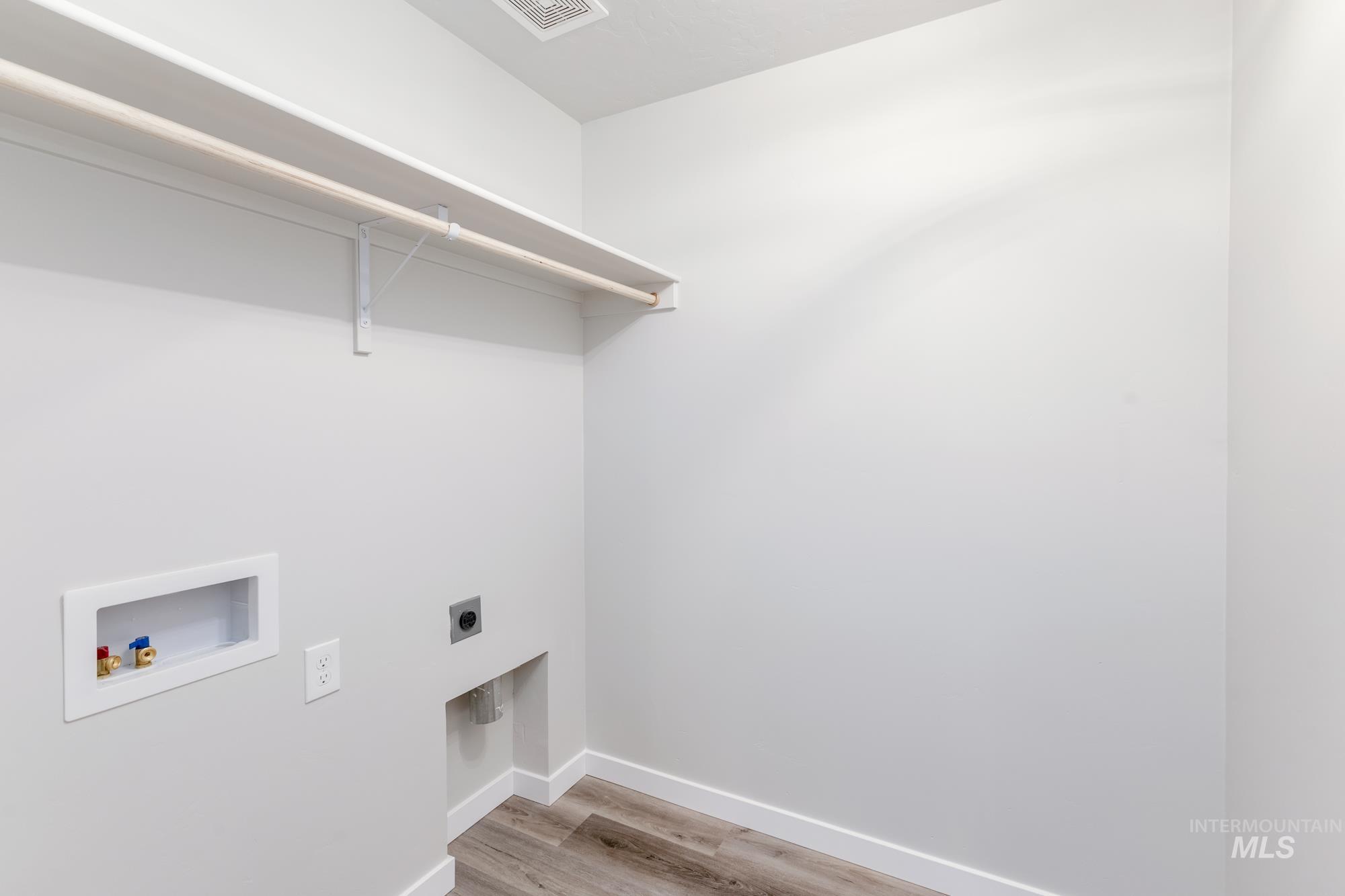 Washroom featuring light wood-type flooring, hookup for a washing machine, and electric dryer hookup