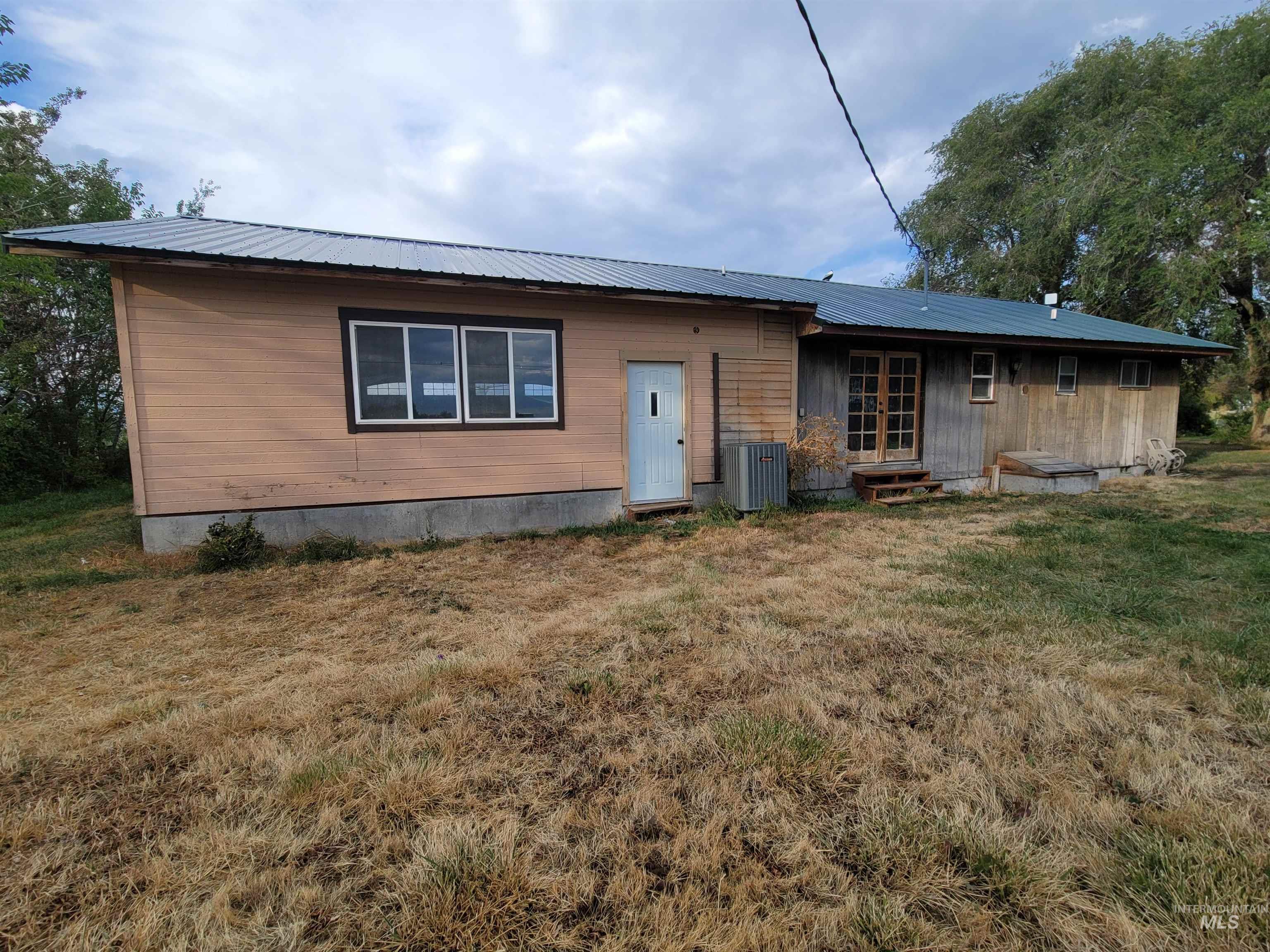 View of front facade with a front yard, entry steps, and a metal roof