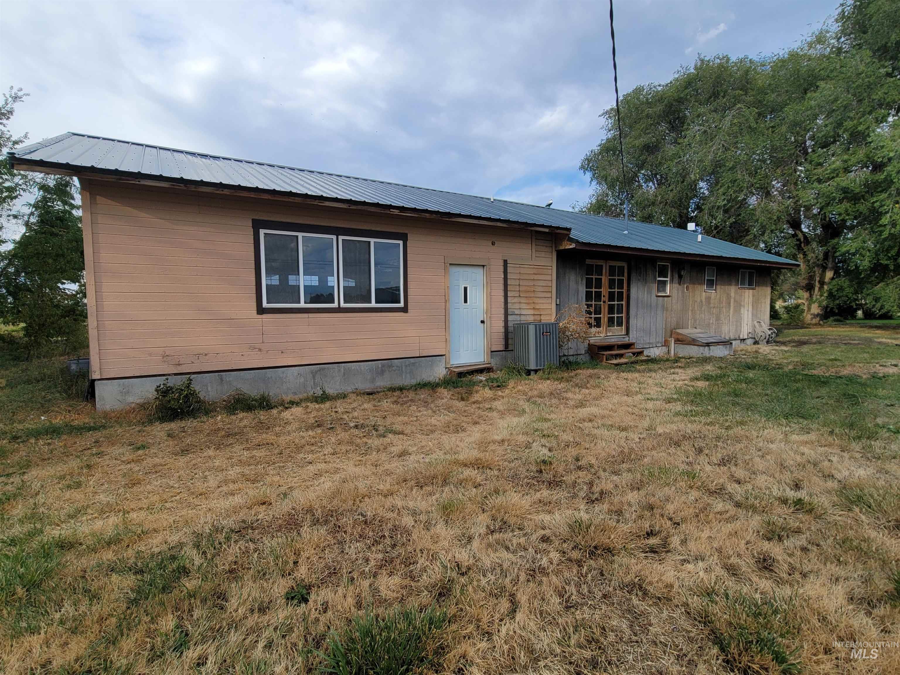 Rear view of property featuring a lawn, entry steps, and a metal roof