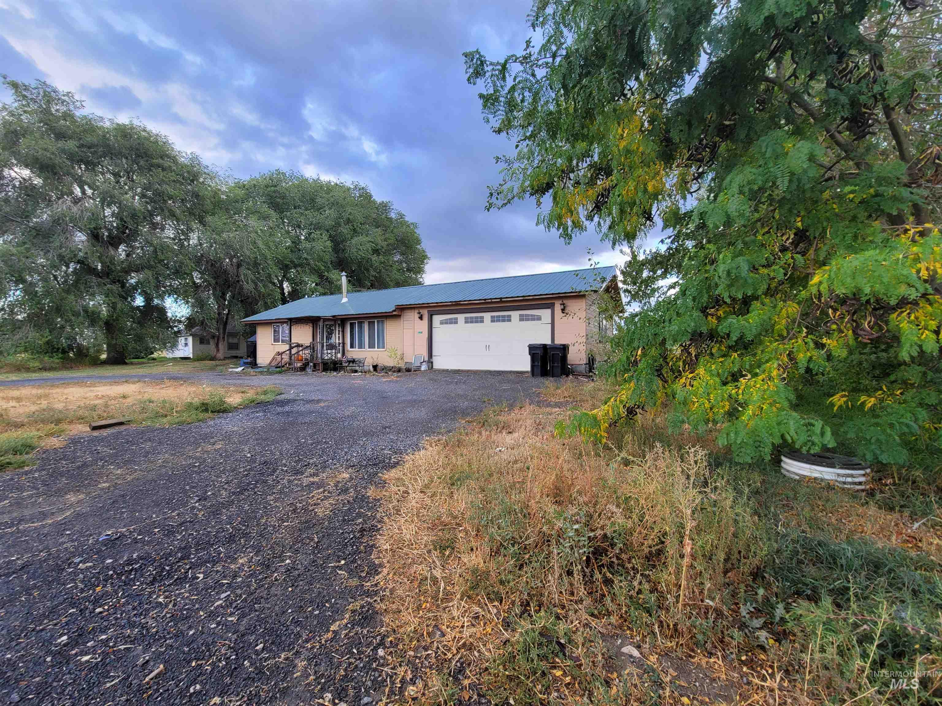 Ranch-style house with driveway, an attached garage, and a metal roof
