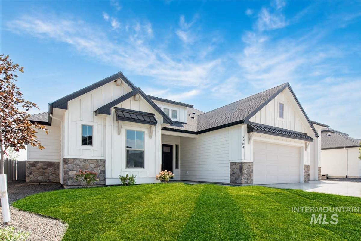 Modern farmhouse featuring a standing seam roof, board and batten siding, stone siding, and a metal roof