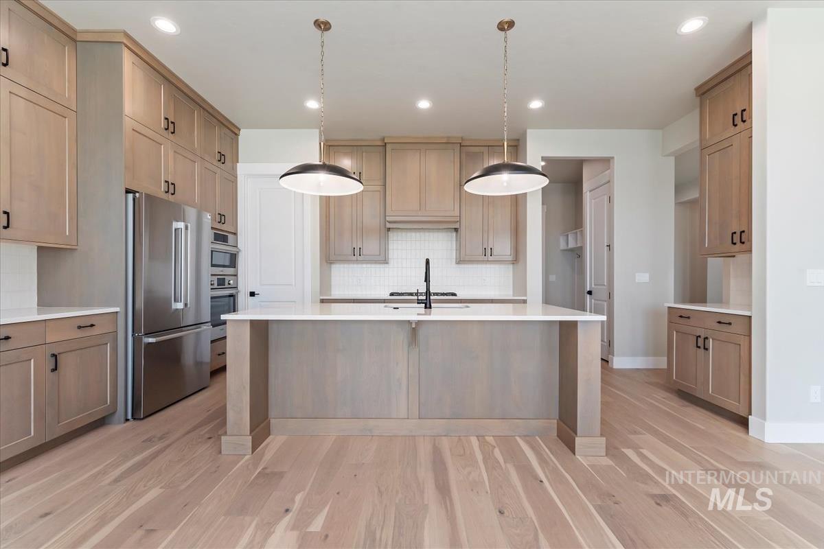 Kitchen with pendant lighting, stainless steel appliances, light stone counters, recessed lighting, and decorative backsplash