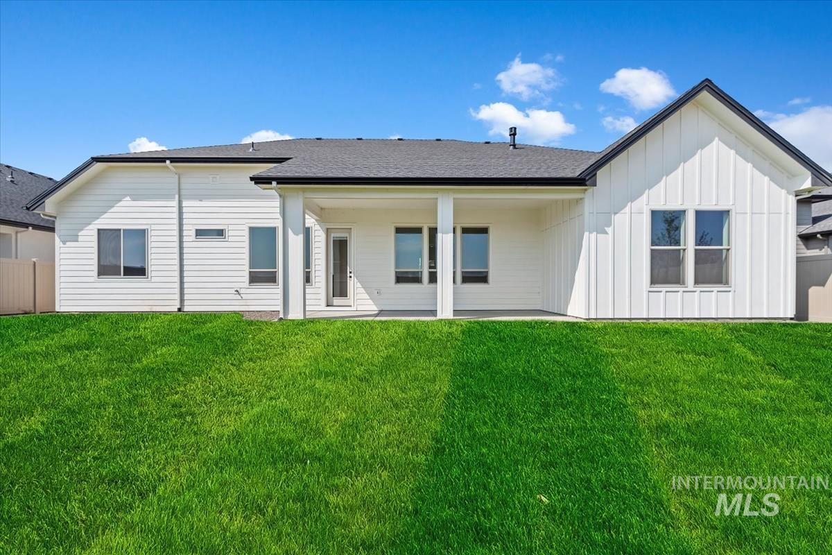 Rear view of property featuring a patio, board and batten siding, and a shingled roof