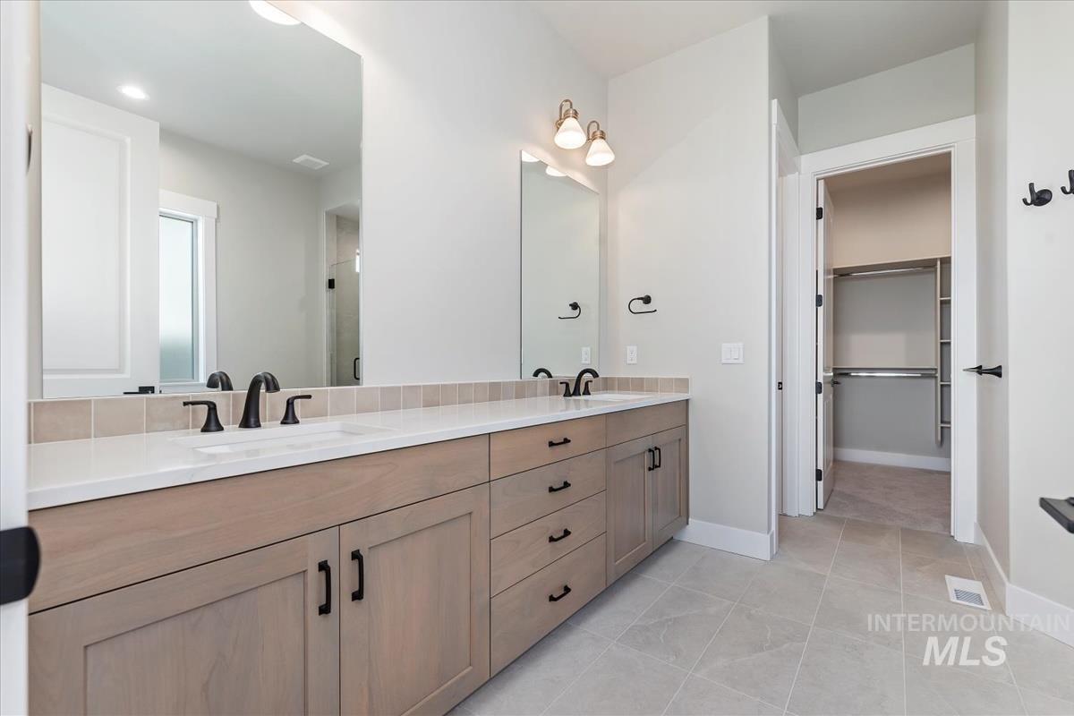 Full bathroom with double vanity, light tile patterned flooring, a walk in closet, a shower stall, and recessed lighting