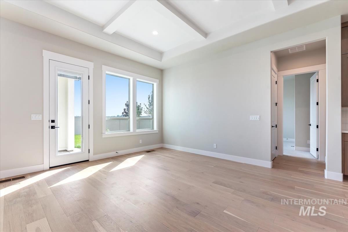 Empty room featuring light wood finished floors, beamed ceiling, and coffered ceiling