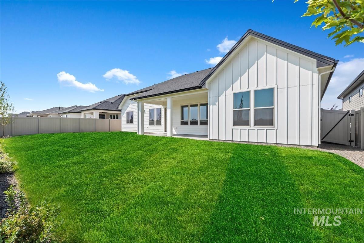 Rear view of house with board and batten siding, a patio area, and a gate