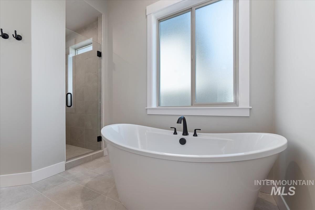 Full bathroom featuring a soaking tub, a shower stall, and tile patterned flooring