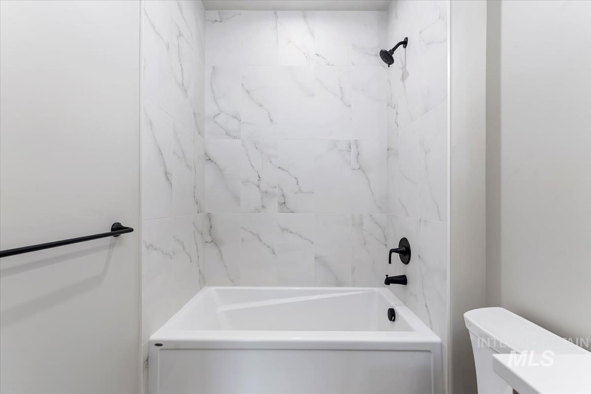 Bathroom featuring washtub / shower combination and toilet