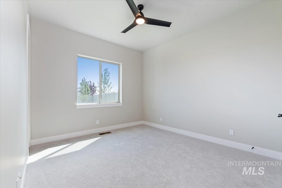 Empty room featuring carpet floors and a ceiling fan