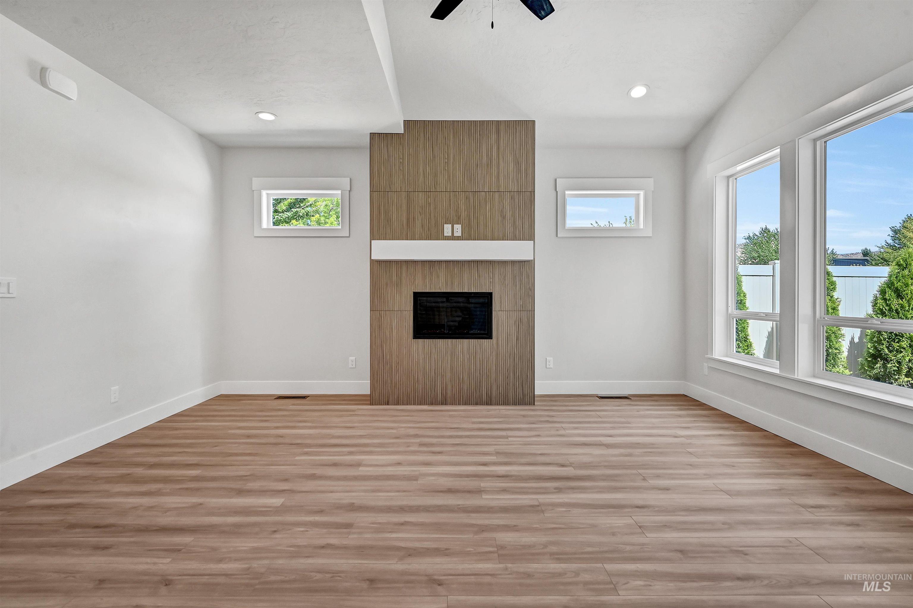 Unfurnished living room featuring light wood-style floors, a large fireplace, ceiling fan, and recessed lighting