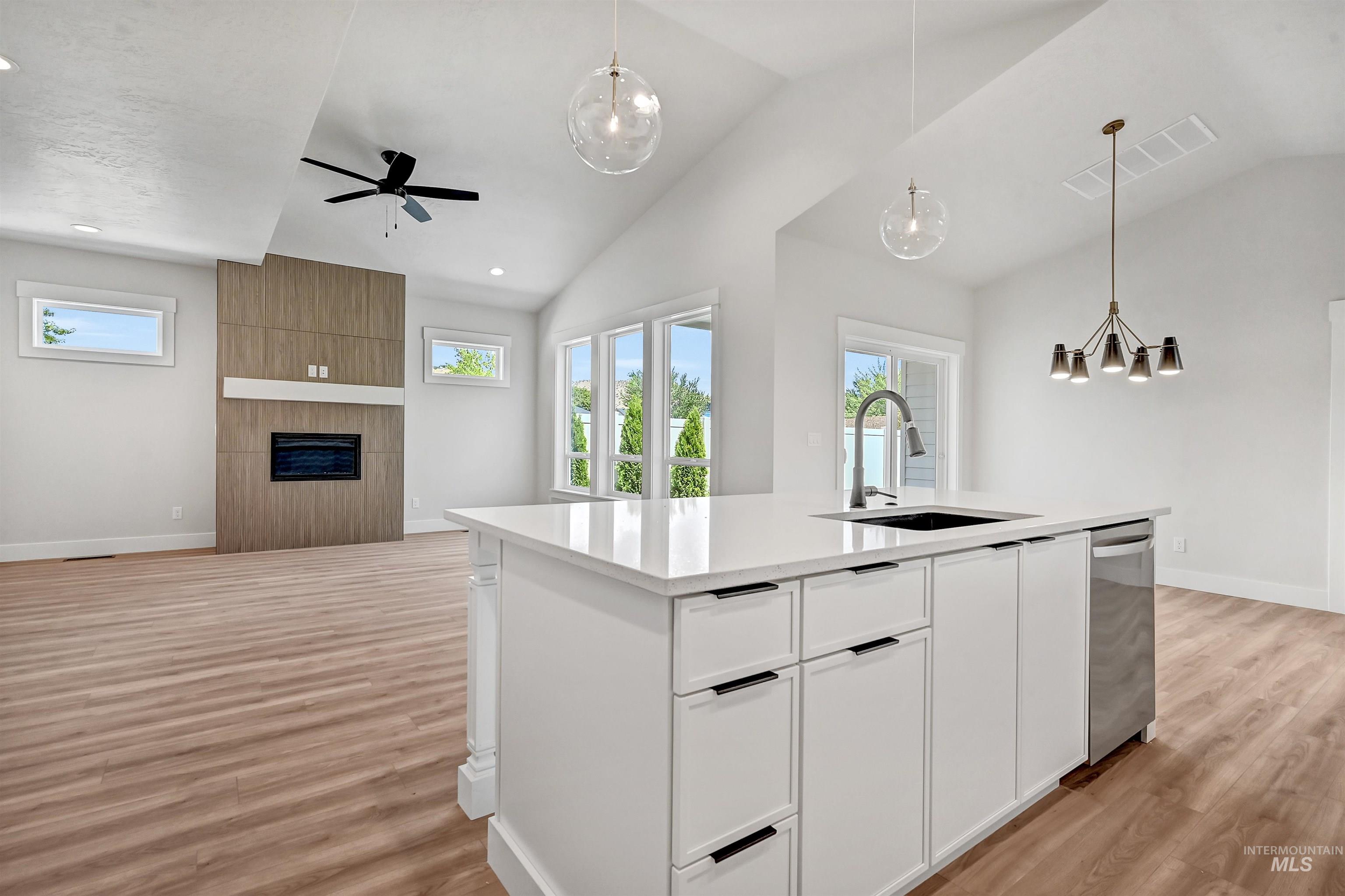 Kitchen featuring open floor plan, pendant lighting, white cabinets, lofted ceiling, and ceiling fan