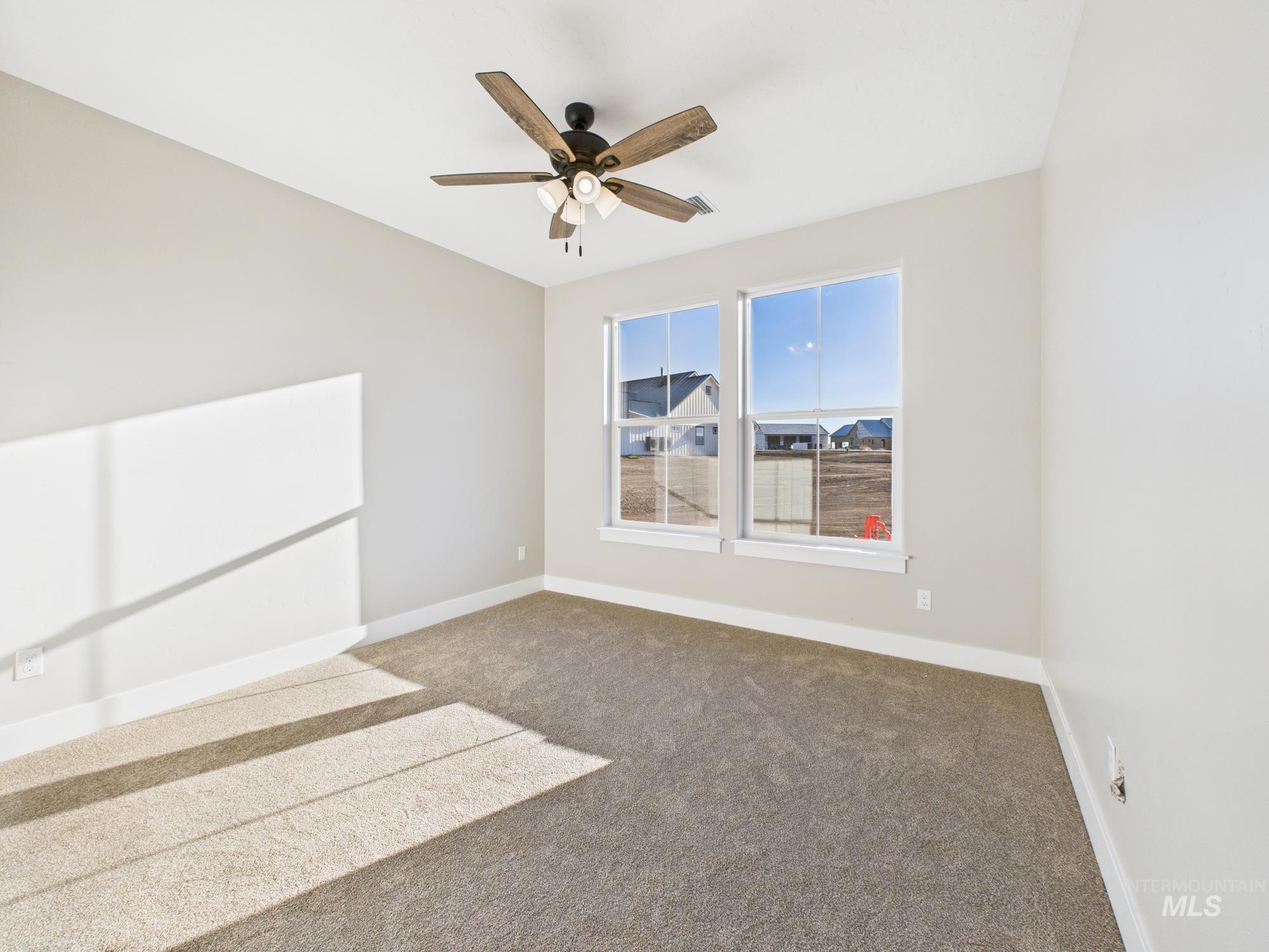 Carpeted empty room with baseboards and ceiling fan