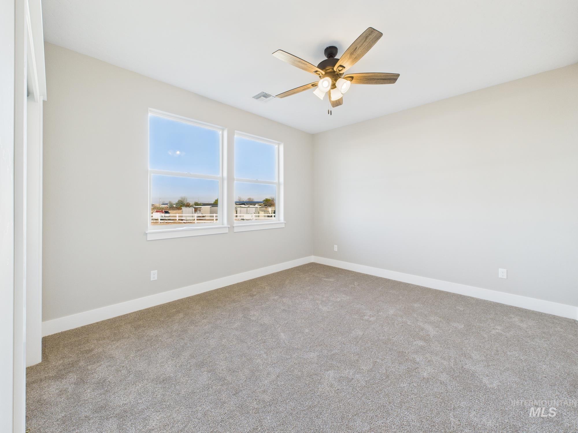 Carpeted spare room with baseboards and ceiling fan