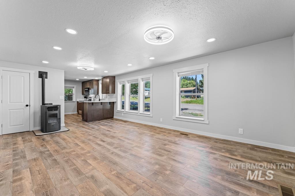 Kitchen featuring open floor plan, dark brown cabinets, light countertops, a peninsula, and a textured ceiling