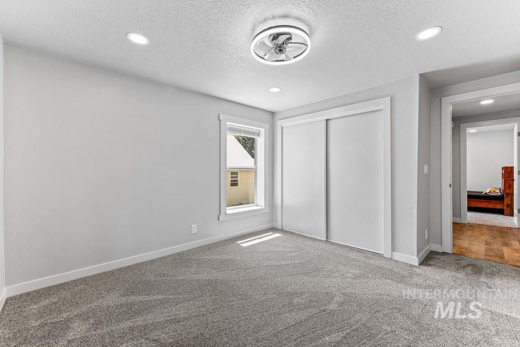 Unfurnished bedroom with a textured ceiling, carpet flooring, a closet, and recessed lighting